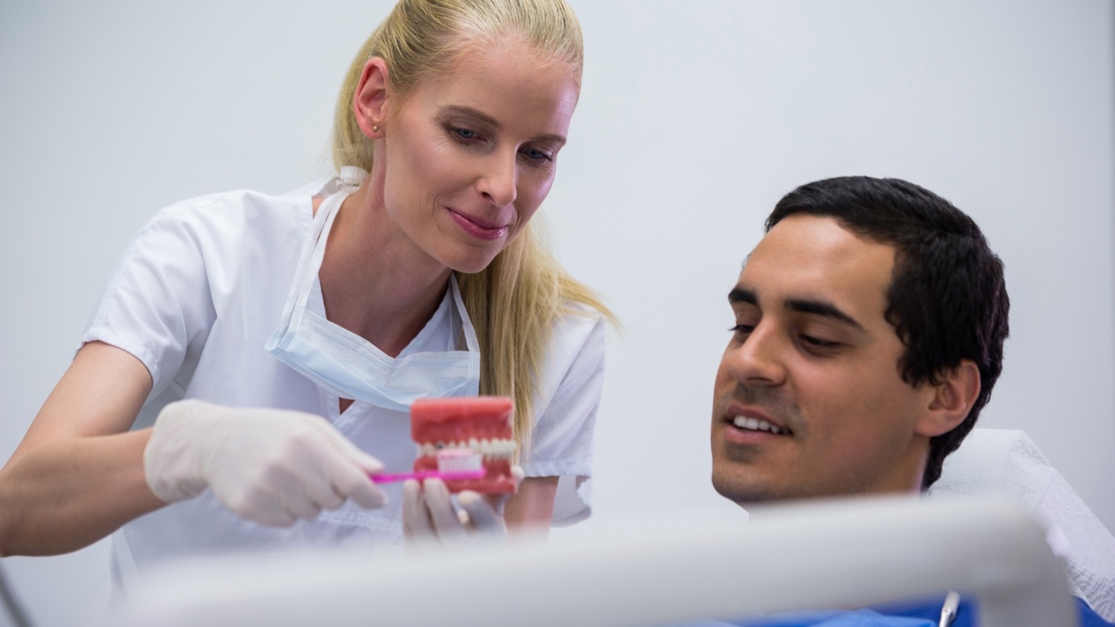 Dentiste presentant un modele de dents au patient